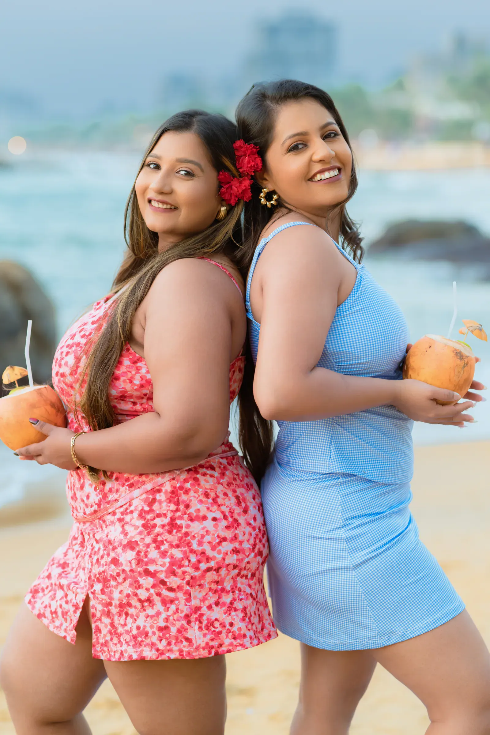 Two women in Darlu swimwear holding coconuts by the beach